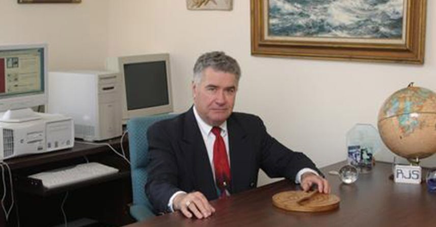 Man sitting at desk with globe, computers.